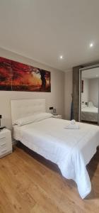 a bedroom with a large white bed with a painting on the wall at Apartamentos Marta in Ribadeo