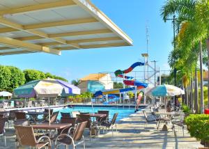 a pool with tables and chairs and a water slide at Nobrezafiori Diroma FIORI taxas de Roupas de Cama Banho e taxas do hotel valor a pagar na recepcao do hotel OBS MENOR DE 18 anos desacompanhado dos pais tem que ter autorizacao com RECONHECIMENTO de firma no cartório in Caldas Novas