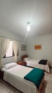 伊瓜苏Triana Guest House的有两张床和一扇窗户的卧室