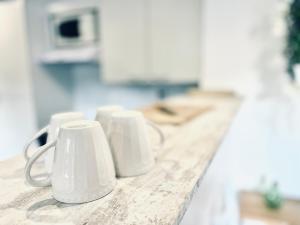 a row of white coffee mugs sitting on a counter at Kapuccino Appartement Chic et Cosy Centre-ville WIFI in Chalencon