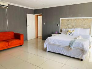 a bedroom with a large bed and an orange chair at Nteto guesthouse in Dwarsloop
