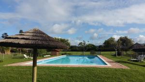 an umbrella next to a swimming pool with grass at Brenton Lake Holiday Cottages in Brenton-on-Sea