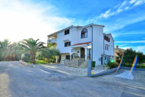 a white house with two flags in the street at Apartments and a Room Ina in Zadar