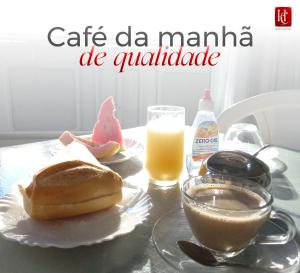 a table with a plate with a sandwich and a drink at Hotel Central Abaetetuba in Abaetetuba