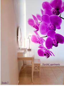a room with a desk with purple orchids on the wall at Orchid Apartments in Thérmi