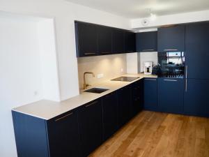 una cucina con armadi blu scuro e ripiani bianchi di Magnifique appartement T4 vue mer et parking privé a Le Touquet-Paris-Plage