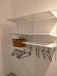 a closet with white shelves and a basket on the wall at A casa tutti bene in Trapani