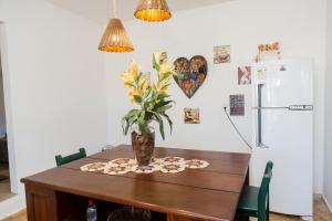 ein Esstisch mit einer Vase mit einer Pflanze darauf in der Unterkunft Casa Vila do Sol - 4 suítes - Praia da Taíba in Taíba