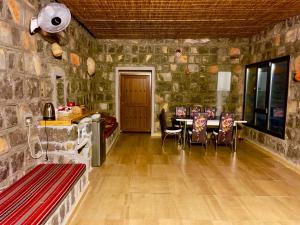 a room with a stone wall with a table and chairs at Jebel shams Sky in Misfāh