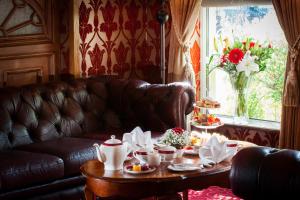 Meadow Court Hotel في لوجهيرا: غرفة معيشة مع أريكة جلدية وطاولة مع أطباق