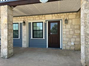 una casa con una puerta azul y una pared de piedra en Quaint studio in Hill Country, en Fredericksburg