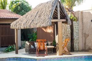 eine Hütte mit Stühlen und einem Tisch neben einem Pool in der Unterkunft Casa Vila do Sol - 4 suítes - Praia da Taíba in Taíba
