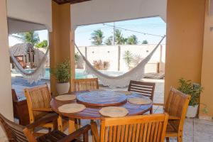 ein Esszimmer mit Tisch und Stühlen und einer Hängematte in der Unterkunft Casa Vila do Sol - 4 suítes - Praia da Taíba in Taíba