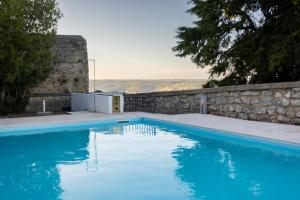 a large blue swimming pool next to a stone wall at Pousada de Ourém - Fátima in Ourém