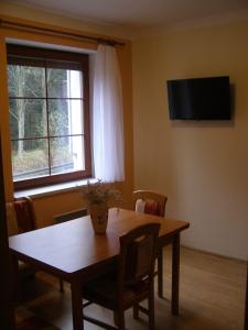 een eetkamer met een houten tafel en een raam bij Rodinné Apartmány in Deštné v Orlických horách