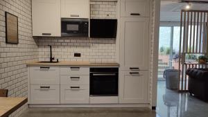 a kitchen with white cabinets and black appliances at Herminia Fariña cerca Sanxenxo in Meaño