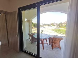 una puerta de cristal que da a un patio con mesa y sillas en Vina Oliva Resort, en Pissouri
