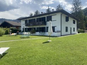 a white house with a umbrella in the grass at [Fronte lago]ResidenceGarden, moderno appartamento in Calceranica al Lago