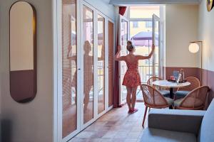 a woman in a red dress looking out of a window at Aparthotel AMMI Vieux Nice in Nice