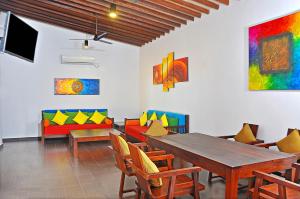 a dining room with a table and chairs and paintings at The Beach Cabanas Retreat & Spa in Koggala