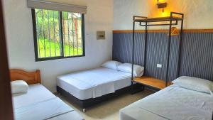 a room with two beds and a window at Finca Turística Peñoles - Cerca de Charcos y Cascadas - Finca Rústica en San Carlos, Antioquia in San Carlos