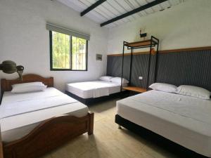 a bedroom with two beds and a window at Finca Turística Peñoles - Cerca de Charcos y Cascadas - Finca Rústica en San Carlos, Antioquia in San Carlos