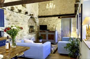 a living room with white furniture and a stone wall at Petite Maison de Mouton in Azat-le-Riz
