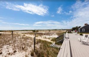 a wooden deck with two chairs and a house at Serene Condo for Cozy Cape Getaway in Truro +9 photos