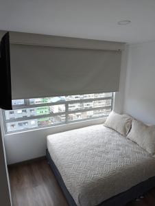 a bedroom with a bed and a large window at Comodo Loft con vista al Skyline de Bogotá in Bogotá