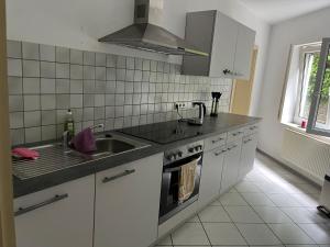 a white kitchen with a sink and a stove at Monteurswohnung Ferienwohnung in der Mitte Deutschlands nahe der A3 in Hünfelden