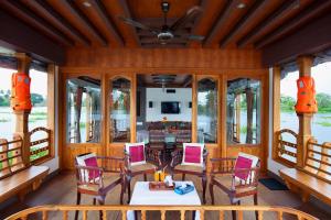 a dining room with a table and chairs and windows at Abad Premium House Boat in Kumarakom