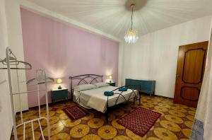 a bedroom with a bed and two tables and a chandelier at House Le Gallinelle in Assemini