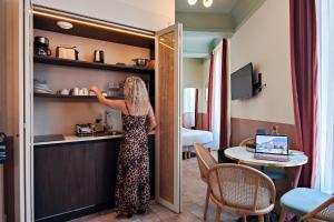 a woman in a dress reaching into a shelf in a hotel room at Aparthotel AMMI Vieux Nice in Nice