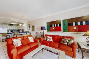 a living room with two orange couches and a kitchen at The Enclave 606 in Orange Beach