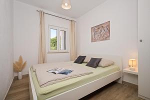 a white bedroom with a large bed with a window at Apartments Leonardo in Rabac