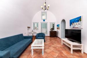 a living room with a blue couch and a tv at Blue Vine Villa Pool Breakfast in Kamari