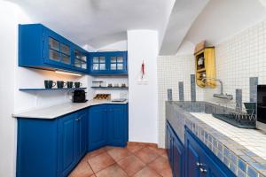 a kitchen with blue cabinets and a tile floor at Blue Vine Villa - Private Pool - Panoramic Sea View in Kamari