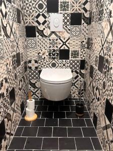 a bathroom with a toilet in a black and white tiles at Sauna et SPA en rez-de-jardin au pied de la montagne in Buhl