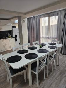 a white dining room table with white chairs and a kitchen at Къща за гости SUNNY HILL in Varna City