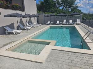 a swimming pool with chairs and umbrellas next to a building at Къща за гости SUNNY HILL in Varna City