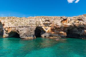 a rocky cliff with two tunnels in the water at La payara di nonna nina in Tiggiano