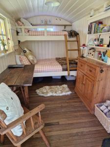 科姆堡The Delkin Shepherds Huts Castle Combe的一间有两张双层床和一张木桌的房间