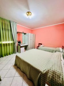 two beds in a room with pink walls and green curtains at Hotel Paradiso in Celano