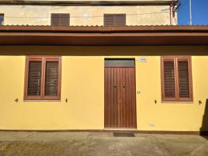 a yellow building with two doors and two windows at La casa di Nenni in Santa Giusta