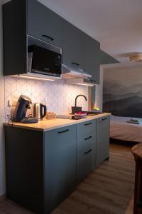 a kitchen with black cabinets and a counter top at Rêverie du Val in Triembach-au-Val +8 photos