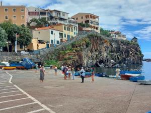 a group of people standing on a beach near the water at Maria's House in Câmara de Lobos