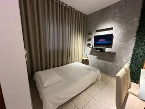 a bedroom with a white bed and a tv at Flat em Americana SP in Americana