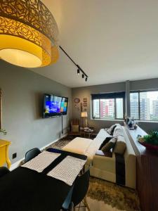 a living room with a couch and a tv at Apto aconchegante no Hotel Mercure in Joinville