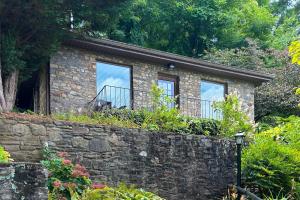 a stone house with two windows and a stone wall at Stone Cottage 1955 in Lake Junaluska