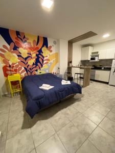 a bedroom with a blue bed and a kitchen at Yvy Porã - Alojamiento Urbano in Corrientes